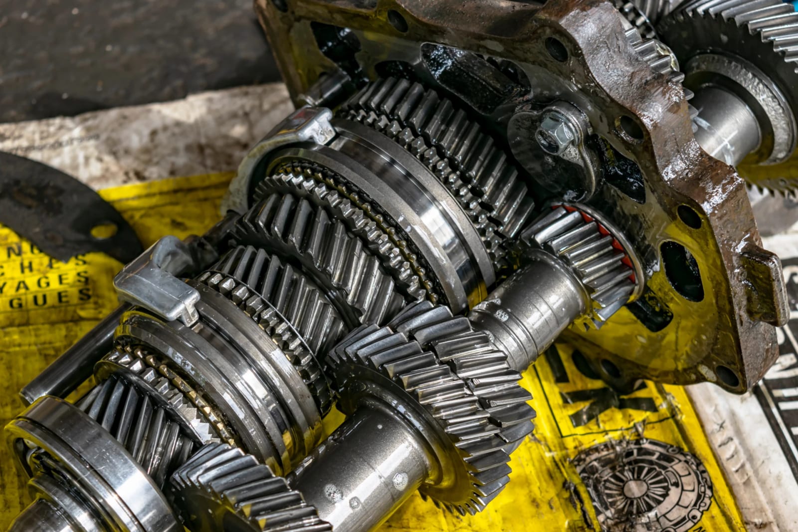 Gear cluster and mainshaft from a stripped manual gearbox laid out on a workshop pallet