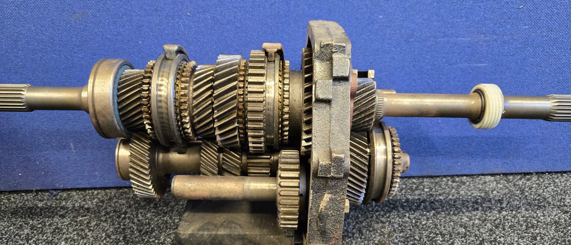 The complete geartrain out of a manual gearbox - input shaft, mainshaft, synchro hubs and countershaft - on a bench stand at The Gearbox Company