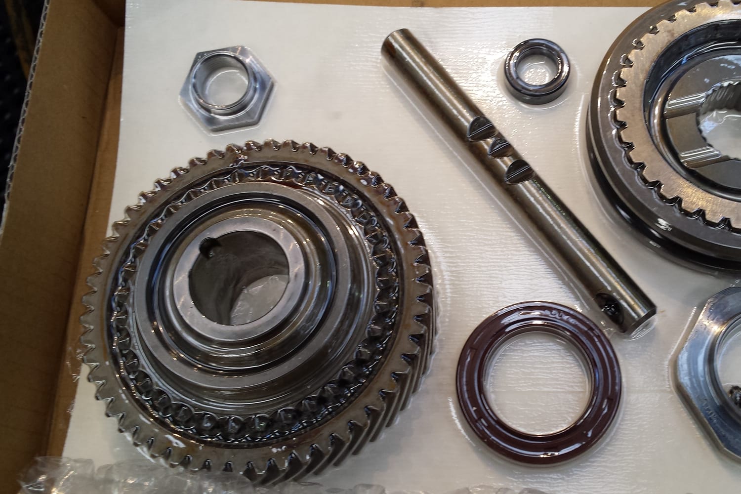 New gear and synchro hub, selector rail, oil seal, bearing and nuts laid out in the box, ready for a rebuild